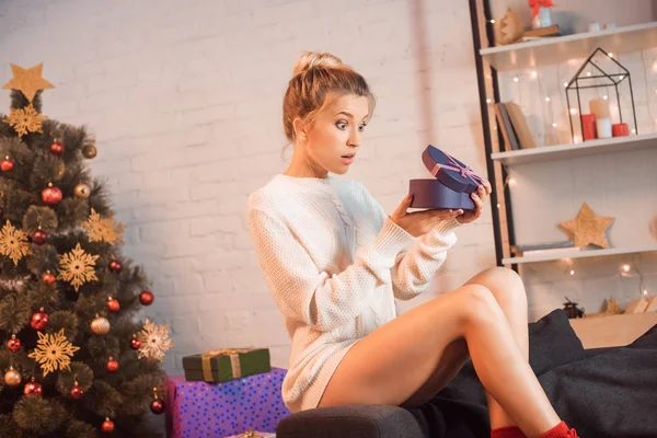 Sorprendida Joven Rubia Sentada Sofá Abriendo Regalo Navidad —  Fotos de Stock