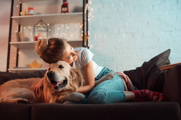 Junge Blonde Frau Auf Der Couch Umarmt Golden Retriever Hund — Stockfoto