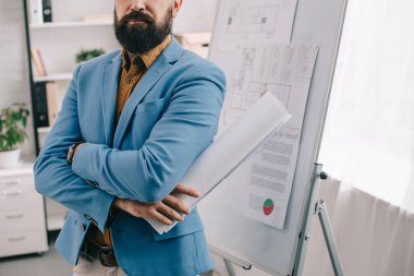 blueprint holding, flip grafiği kullanmayı ve Office proje üzerinde mavi formal giyim yetişkin erkek mimar görünümünü kırpılmış