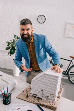 ev modeli üzerinde işaret ve Office proje üzerinde formal giyim gülümseyen yetişkin erkek mimar