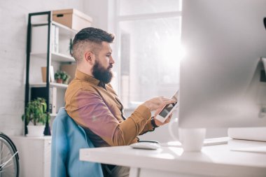 Ofis Masası oturma ve işyerinde dijital tablet kullanarak ciddi yetişkin iş adamı