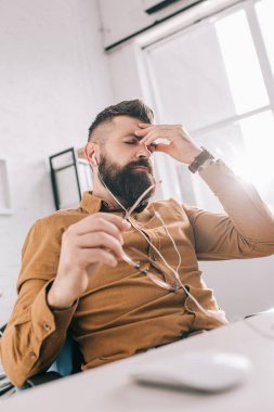 hayal kırıklığına uğramış yetişkin iş adamı earphones ile el işyerinde gözlük
