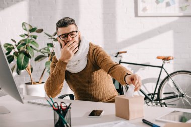 örme eşarp ofis masa başında oturan öksürük ve dokular için uzanarak hasta işadamı 