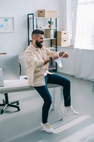 Male office worker tearing papers and sitting on table 