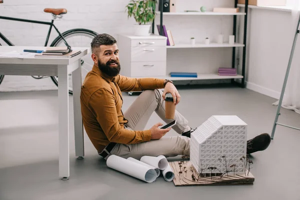 Sonriente Barbudo Adulto Arquitecto Masculino Usando Smartphone Sosteniendo Café Para —  Fotos de Stock