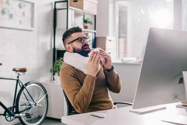 Sick Businessman Knitted Scarf Sitting Office Desk Sneezing — Stock Photo, Image