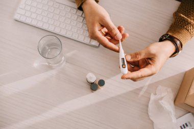 Ofis Masası tıbbi termometre tutan işadamı görünümünü kırpılmış