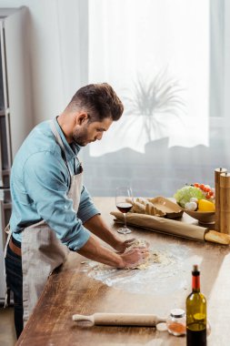 Genç adamın mutfakta hamur hazırlama önlük yüksek açılı görünüş