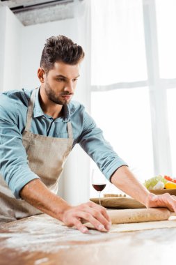 yakışıklı delikanlı oklava tutarak ve mutfakta hamur hazırlama önlük