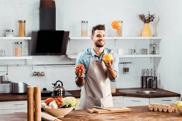 Pemuda Tampan Yang Tersenyum Dengan Celemek Memegang Sayuran Segar Dapur — Stok Foto