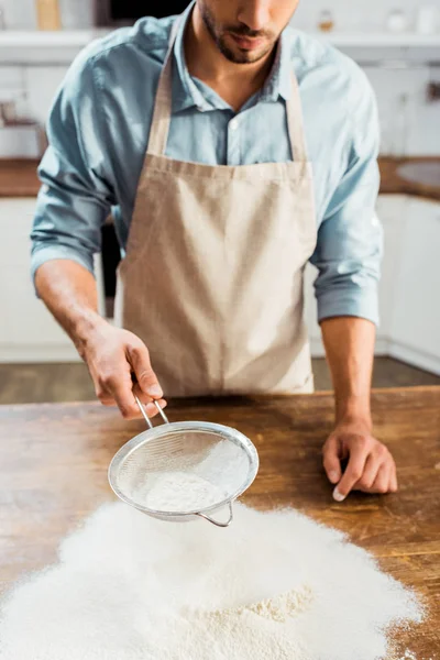 Обрезанный Снимок Молодого Человека Фартуке Просеивающего Муку Кухонном Столе — Бесплатное стоковое фото