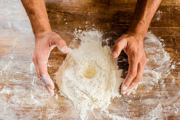 partial view of male hands and flour on kitchen table