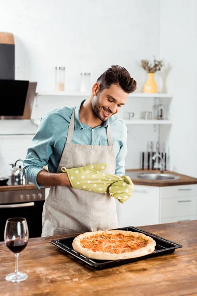 Jovem Sorridente Avental Pegadores Panela Olhando Para Pizza Caseira Fresca — Fotografia de Stock Grátis