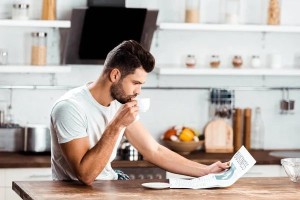 Focalizzato Giovane Che Beve Caffè Legge Giornali Cucina Mattino — Foto stock gratuita