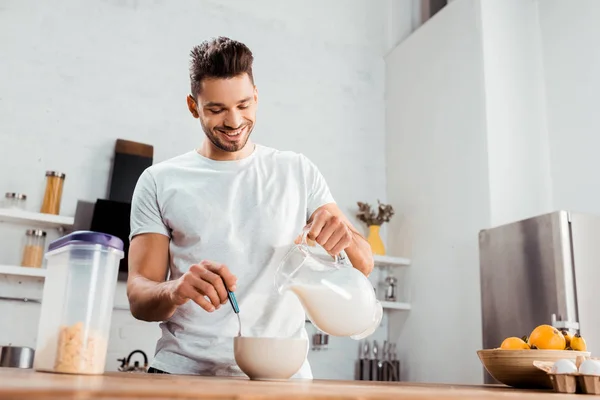 Sonriente Joven Vertiendo Leche Tazón Con Hojuelas Maíz — Foto de Stock