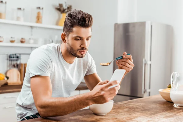 Knappe Jongeman Met Behulp Van Smartphone Ontbijten Thuis — Stockfoto