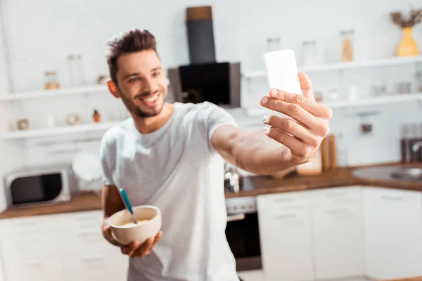 Sonriente Joven Sosteniendo Tazón Con Desayuno Tomando Selfie Con Teléfono — Foto de Stock