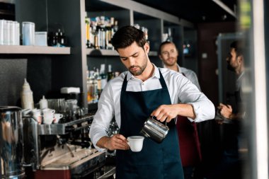 adult barista in apron pouring milk to coffee at workplace clipart