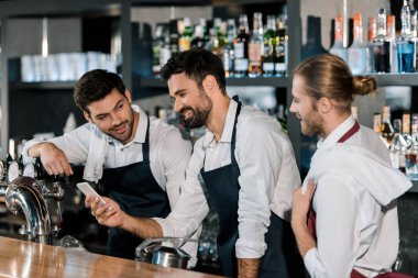 İşyerinde Smartphone kullanarak yakışıklı yetişkin barmen 