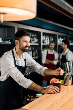 neşeli barmen ahşap kontuarında kokteyl bardağı taşıran damla koyarak