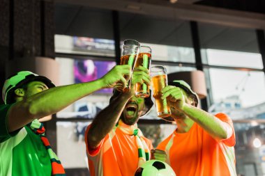 Football fans clinking glasses with lager and cheering in bar clipart