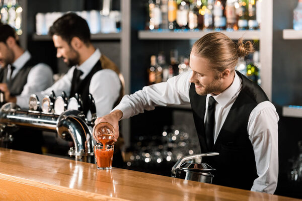 Barman pouring drink in glass on wooden counter
