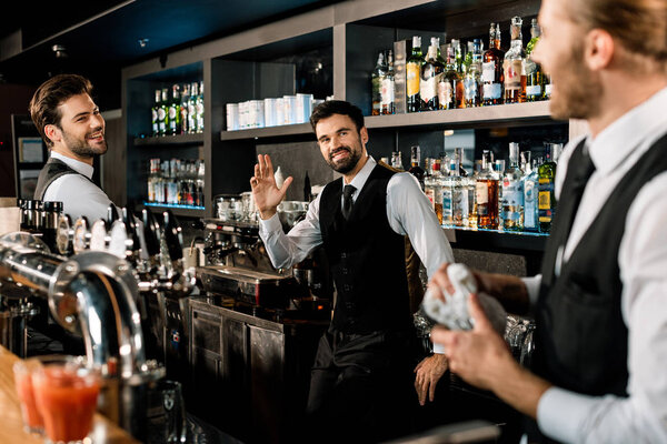 Handsome bartenders standing in bar and smiling