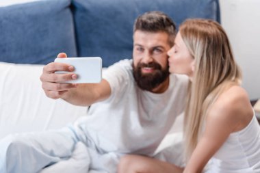 Güzel çift öpüşme ve selfie yatak odasında sabah alarak aşık