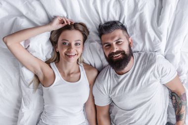 Güzel çift yatakta, gülümseyen ve kameraya bakarak yalan