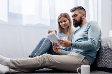 Dijital tablet ve içecekler ile katta oturan çift