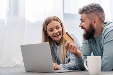 Neşeli aile yerde laptop ile yatarken ve online alışveriş
