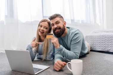 Mutlu çift laptop ile yerde yatarken ve online alışveriş 