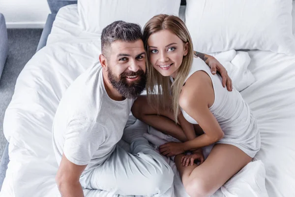 Vista Aérea Feliz Pareja Joven Sentada Cama Blanca Mirando Cámara — Foto de stock gratuita