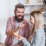 Sonriente pareja divirtiéndose durante el desayuno en la mañana