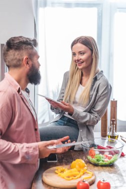 Koca salata ve dijital tablet ile masada oturan karısı hazırlanması
