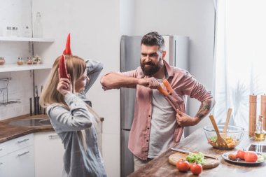funny couple playing with vegetables at kitchen clipart