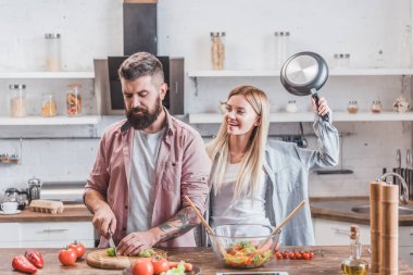 Şaka ve mutfak adama vurmak için metal pan yükselterek kız