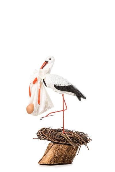 decorative stork holding baby nappy with doll and standing in wicker nest isolated on white