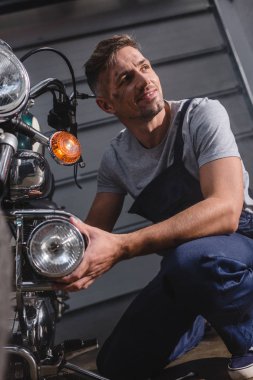 Motosiklet Far garajda sabitleme gülümseyen yetişkin makinist