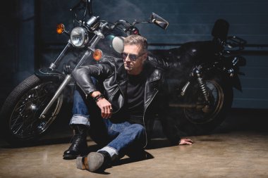 sonraki motosiklet için yakışıklı motorcu katta oturan güneş gözlüğü