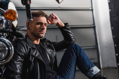 kameraya bakarak ve motosiklet garajda üzerinde eğilerek yakışıklı motorcu