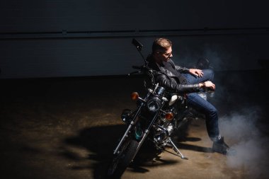 Klasik motosikletçi motosiklet garajında oturan siyah güneş gözlüğü