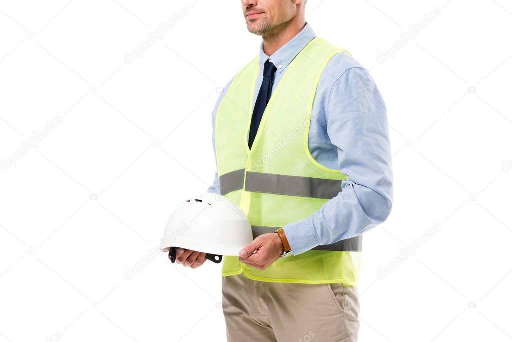 cropped view of engineer in safety vest holding helmet isolated on white