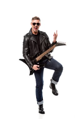 excited stylish man in leather jacket holding electric guitar and showing rock sign isolated on white clipart