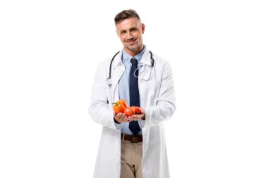 kameraya bakarak ve sebze izole beyaz, sağlıklı beslenme kavramı üzerinde elinde tutan doktor gülümseyen
