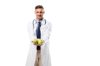 kameraya bakarak ve taze elma izole beyaz, sağlıklı beslenme kavramı üzerinde tutan doktor gülümseyen