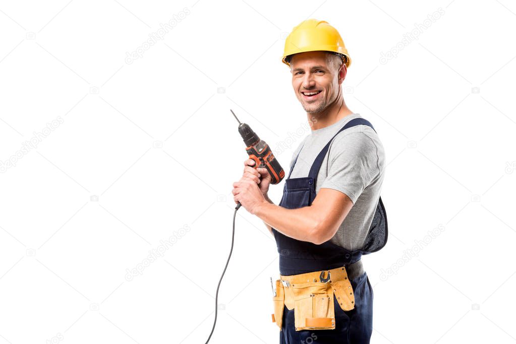 smiling construction worker in helmet holding drill isolated on white