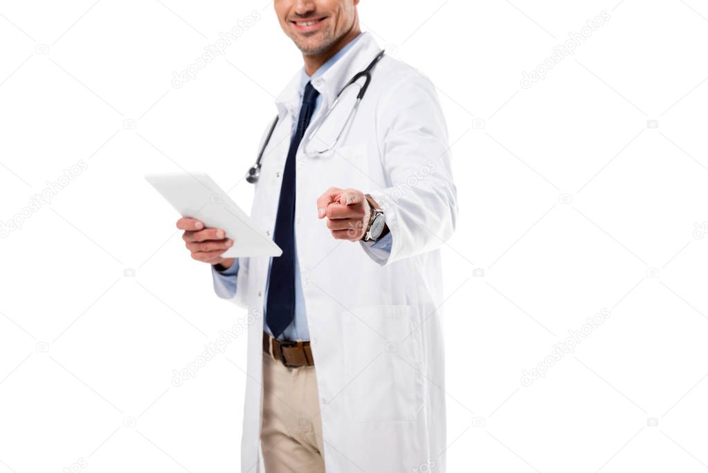 doctor holding digital tablet and pointing at camera with finger isolated on white
