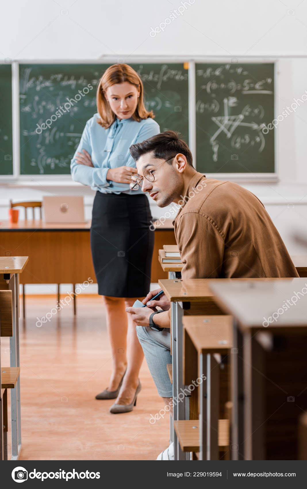 Dissatisfied Female Teacher Arms Crossed Looking Male Student