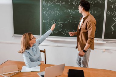 Kadın öğretmen denklemler kara tahta duran öğrenci iken işaret 